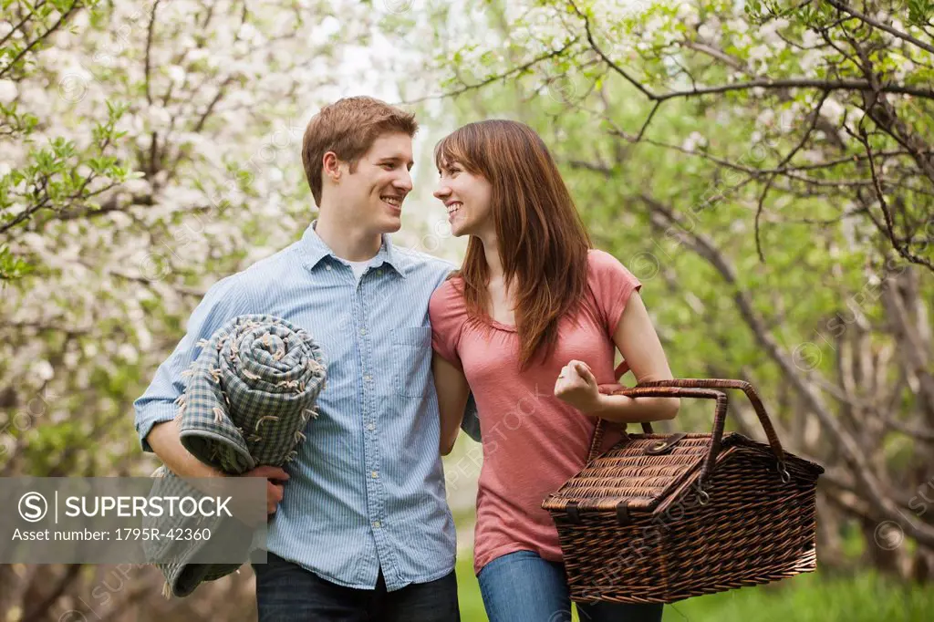 Young couple with picnic basket in orchard