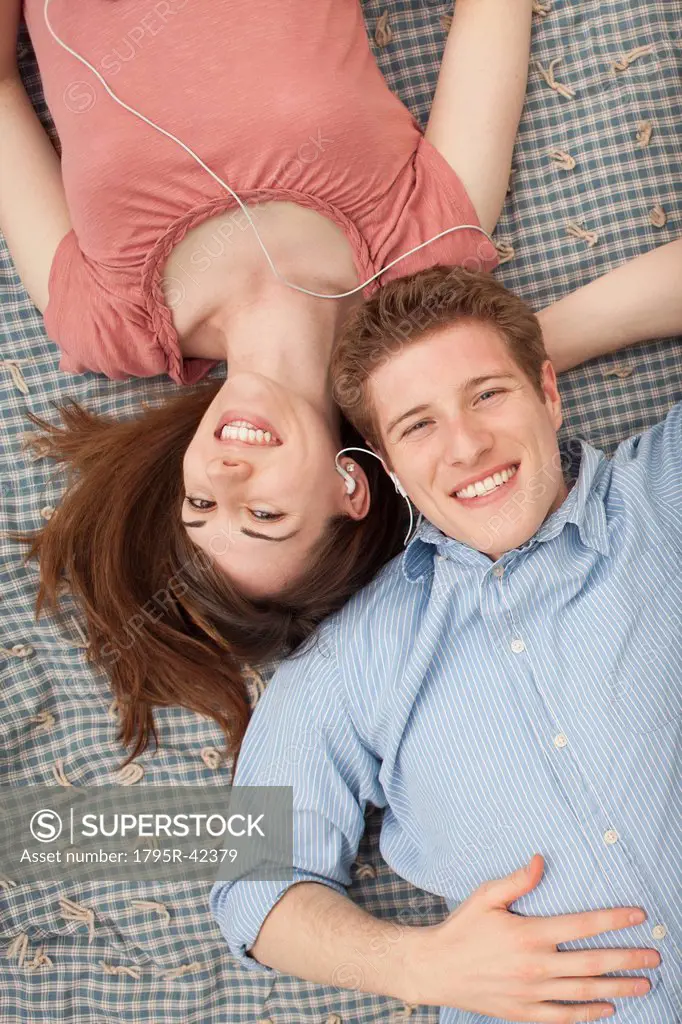 Young couple with mp3 player lying on blanket