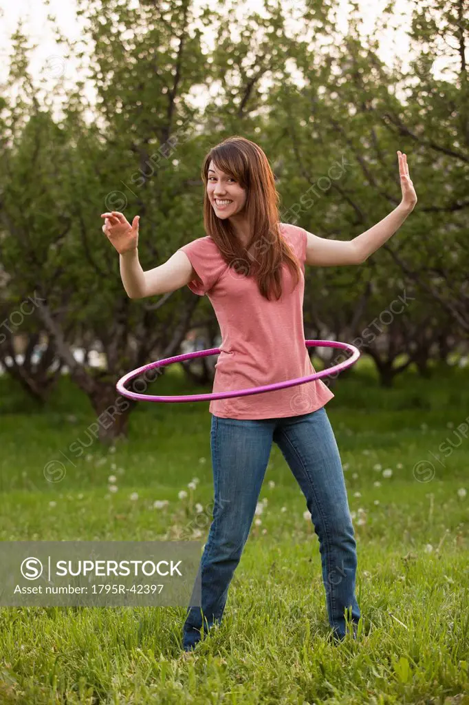 USA, Utah, Provo, Young woman using plastic hoop in orchard