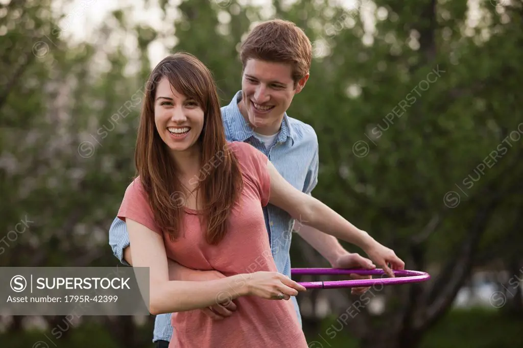 Young couple using plastic hoop in orchard