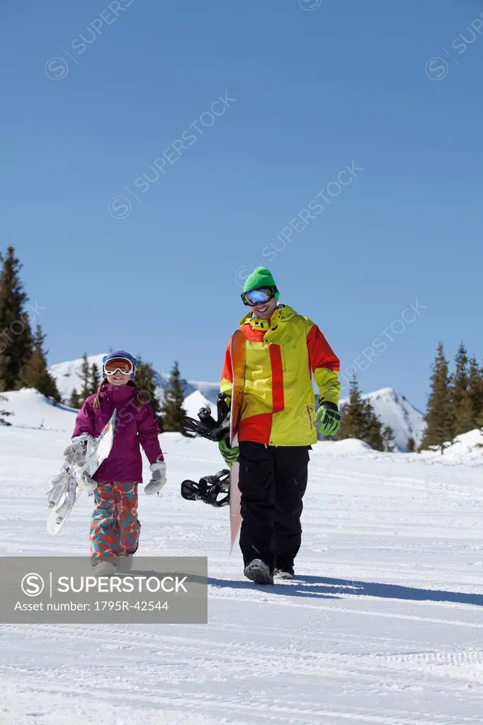 USA, Colorado, Telluride, Father and daughter 10_11 walking with snowboards in winter scenery