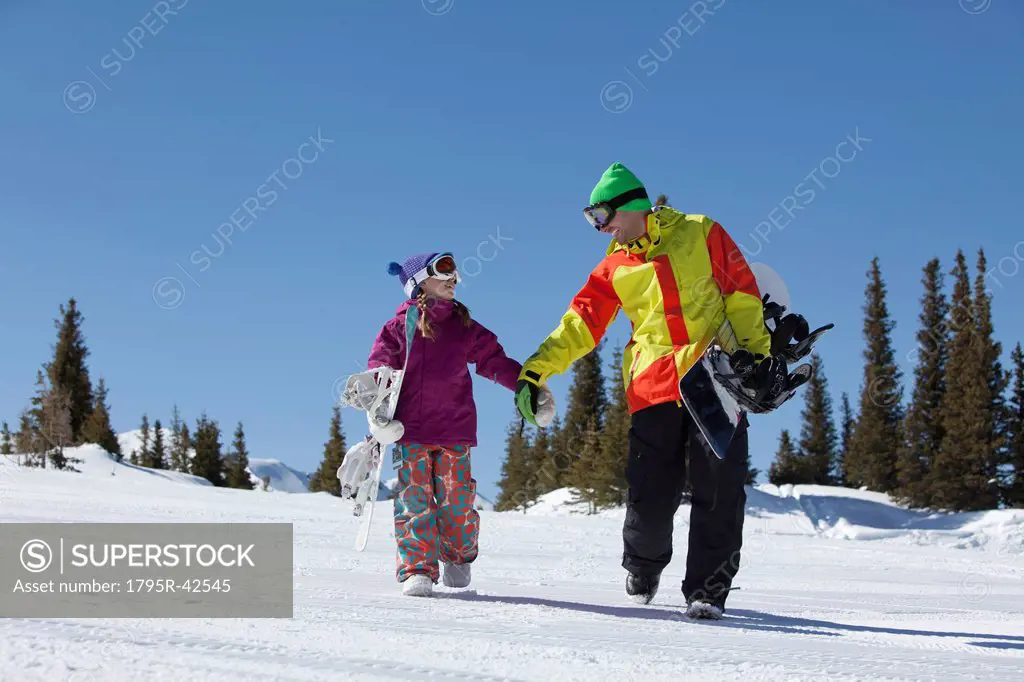 USA, Colorado, Telluride, Father and daughter 10_11 walking with snowboards in winter scenery