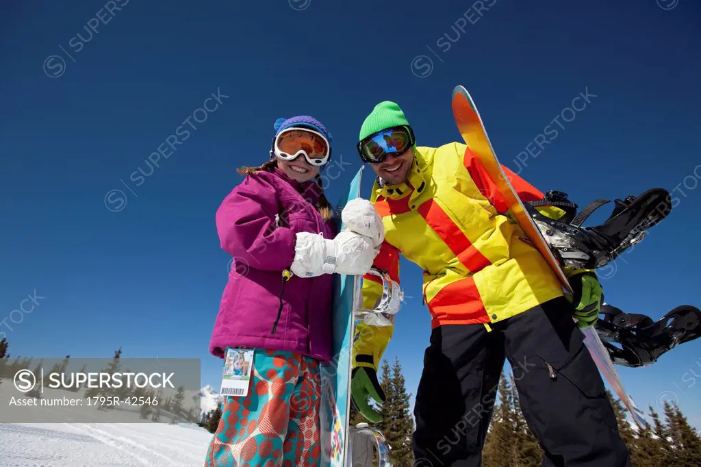 USA, Colorado, Telluride, Father and daughter 10_11 posing with snowboards in winter scenery