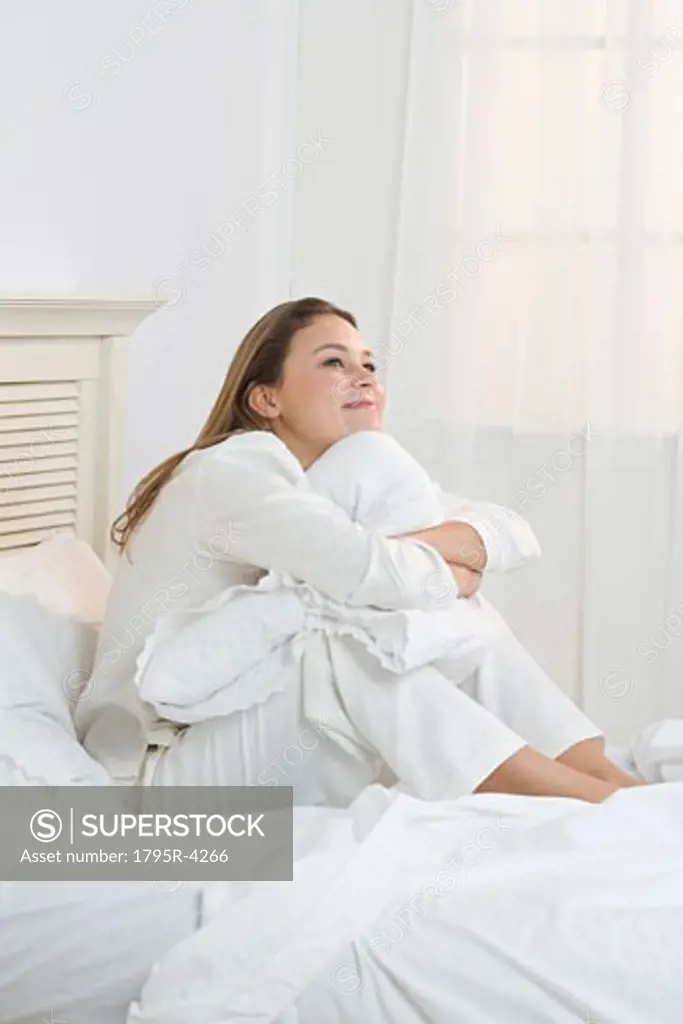 Woman on bed hugging her knees