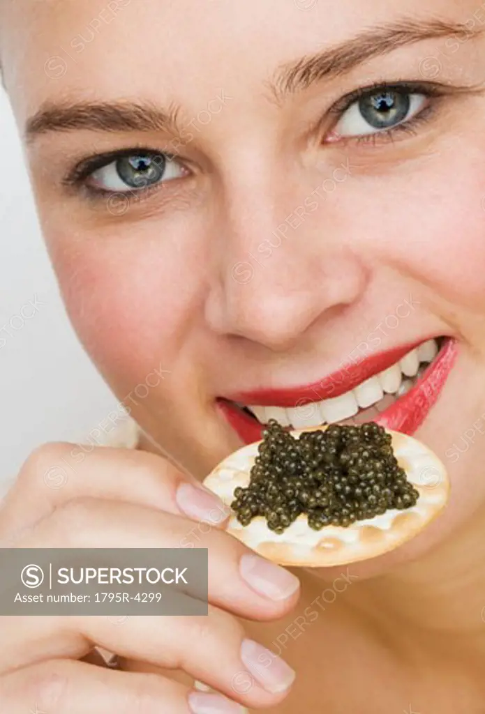 Close-up of woman eating caviar on a cracker