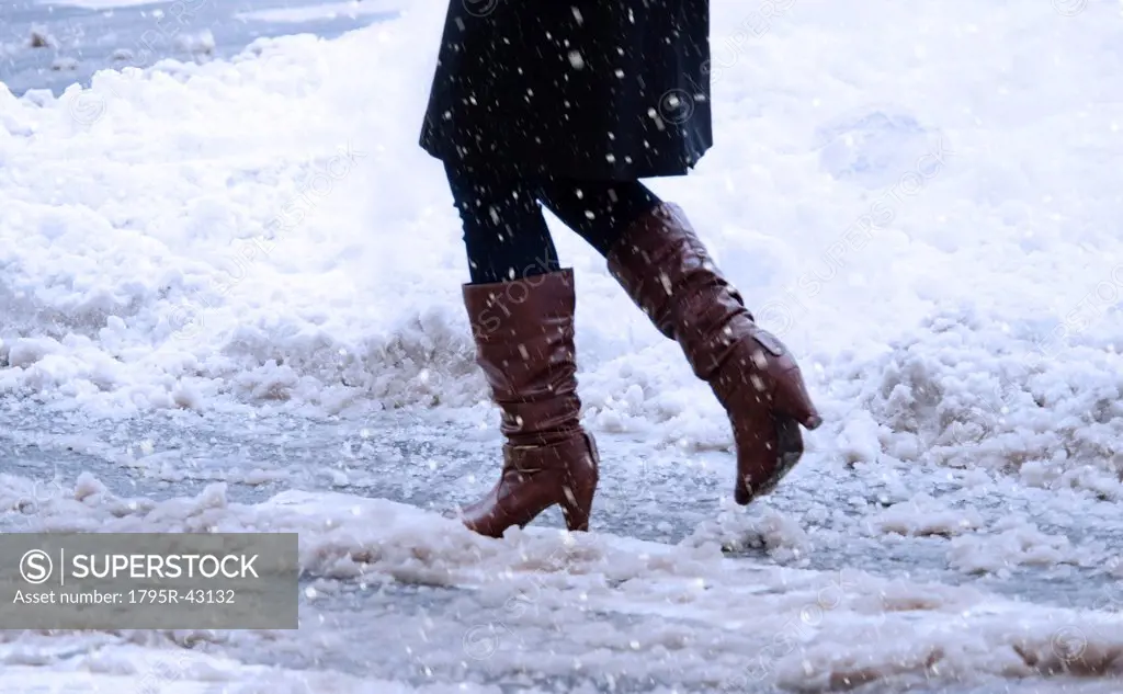 USA, New York, New York City, close up of woman´s legs walking in winter slush
