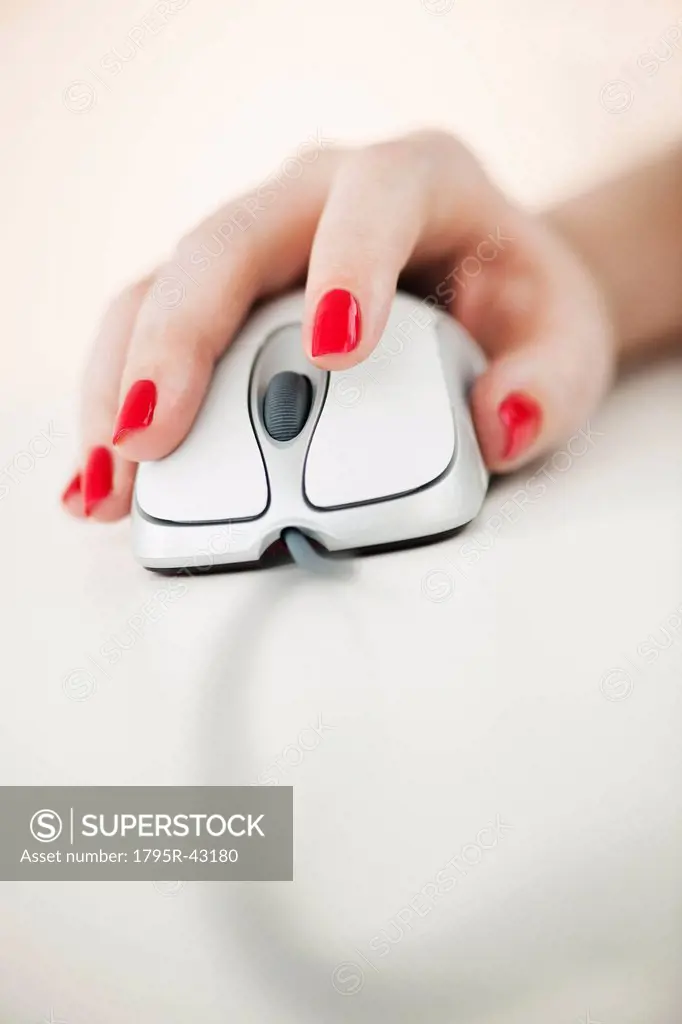 Close up of woman´s hand with red nail polish holding computer mouse