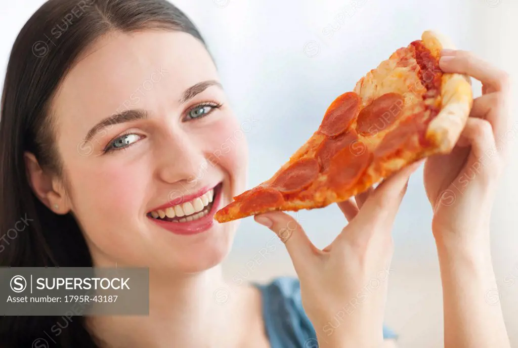 Portrait of smiling young woman eating pizza