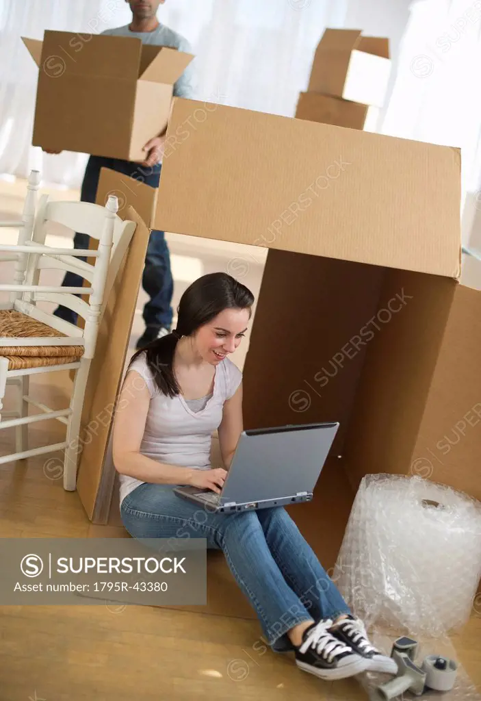 Woman using laptop by cardboard box
