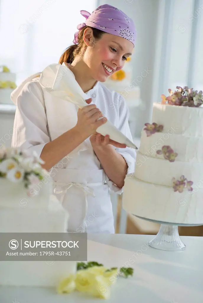 Happy young woman decorating wedding cake