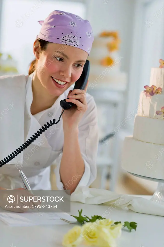 Happy young woman taking order near wedding cake