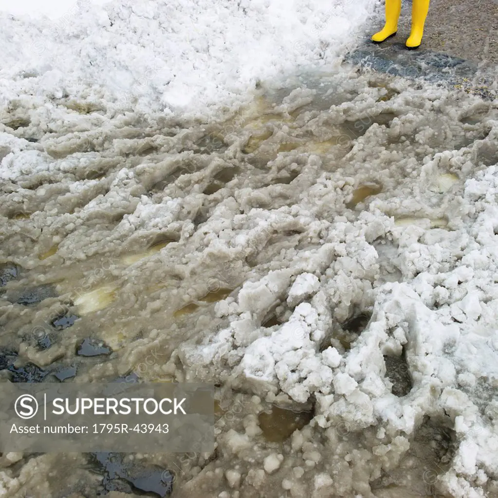 USA, New York, New York City, close up of feet in yellow rubber boots in slush