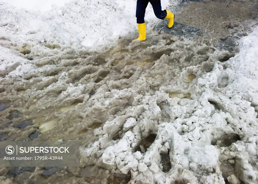 USA, New York, New York City, legs of person in yellow rubber boots walking in slush