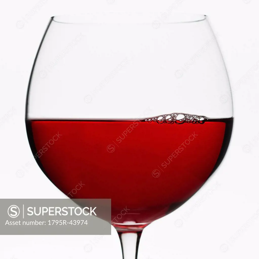 Close up of glass of red wine on white background