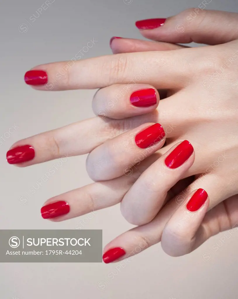 Close up of woman´s clasped hands with red nail polish