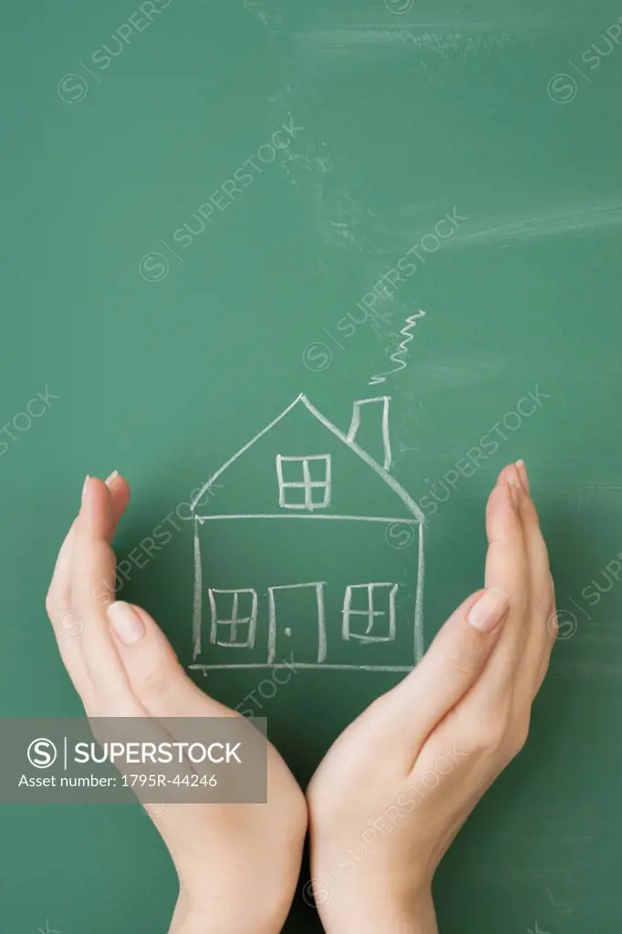 Woman holding hands around house drawn on blackboard