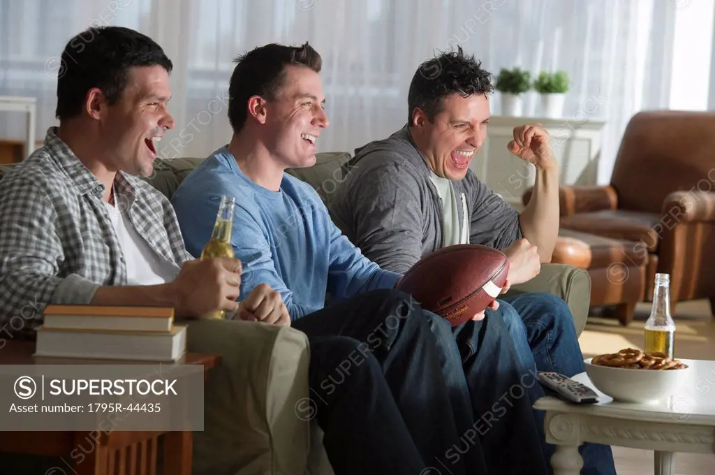 USA, New Jersey, Jersey City, three men watching television