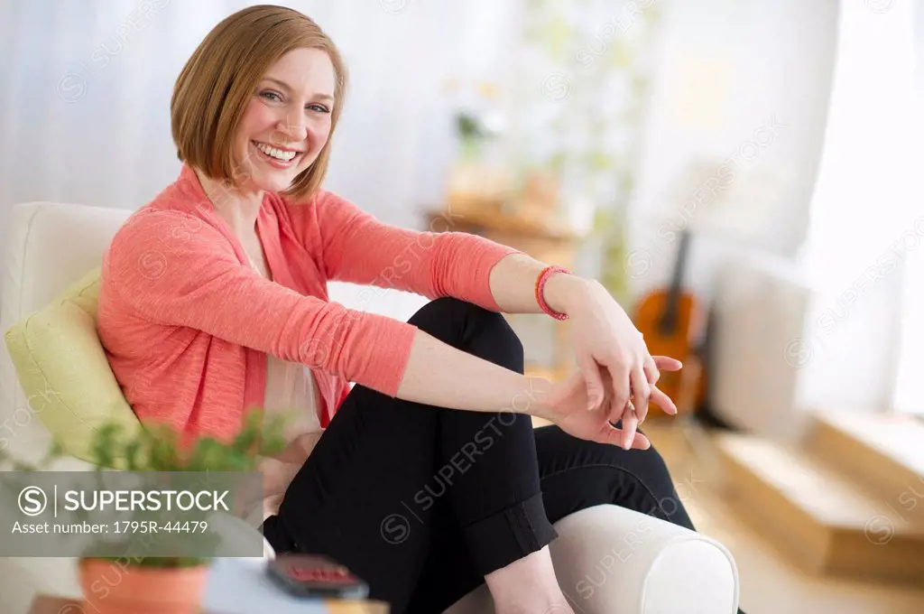 USA, New Jersey, Jersey City, woman sitting on sofa smiling