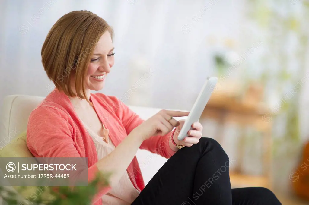 USA, New Jersey, Jersey City, woman sitting on sofa and using digital tablet