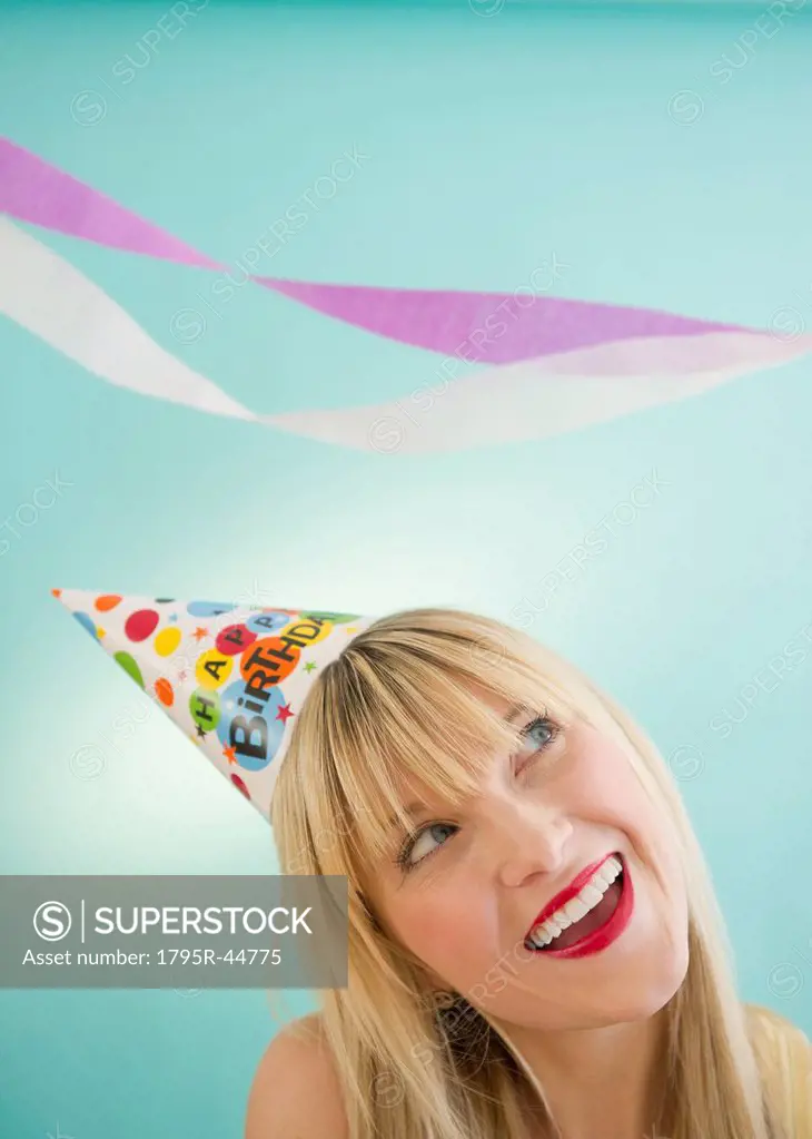 Young woman wearing party hat laughing