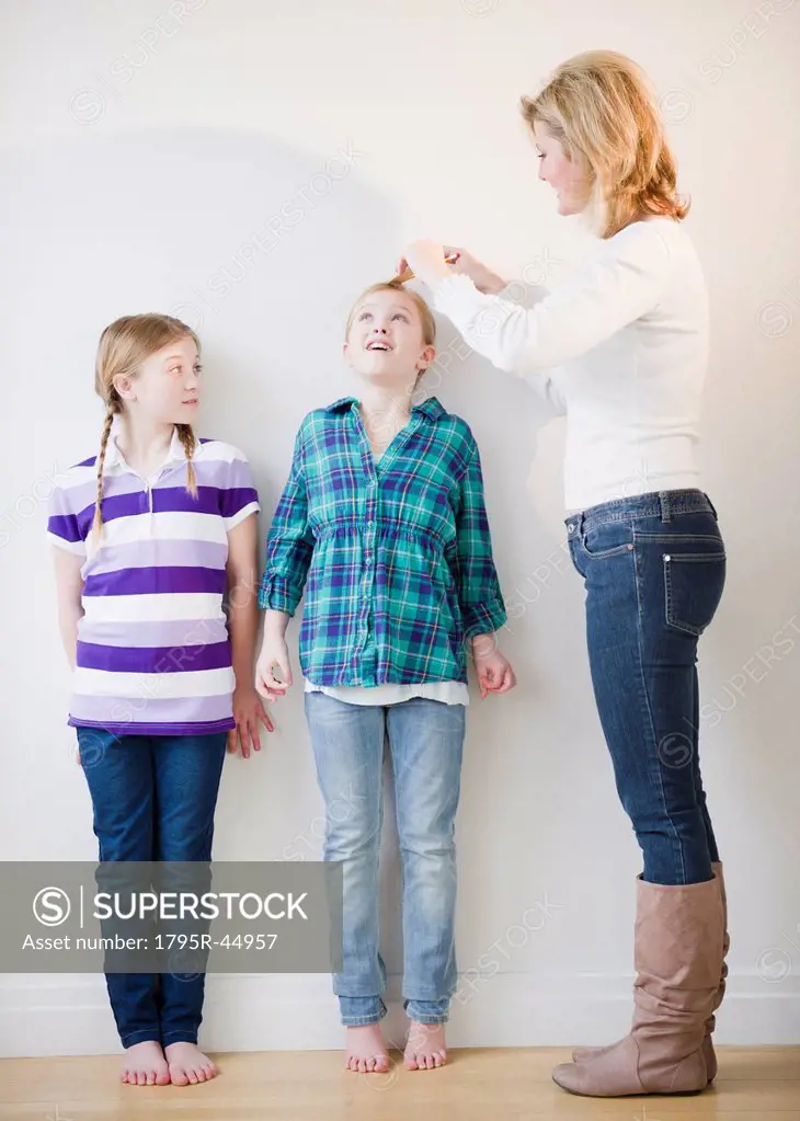 USA, Jersey City, New Jersey, mother measuring daughters´ 8_11 height
