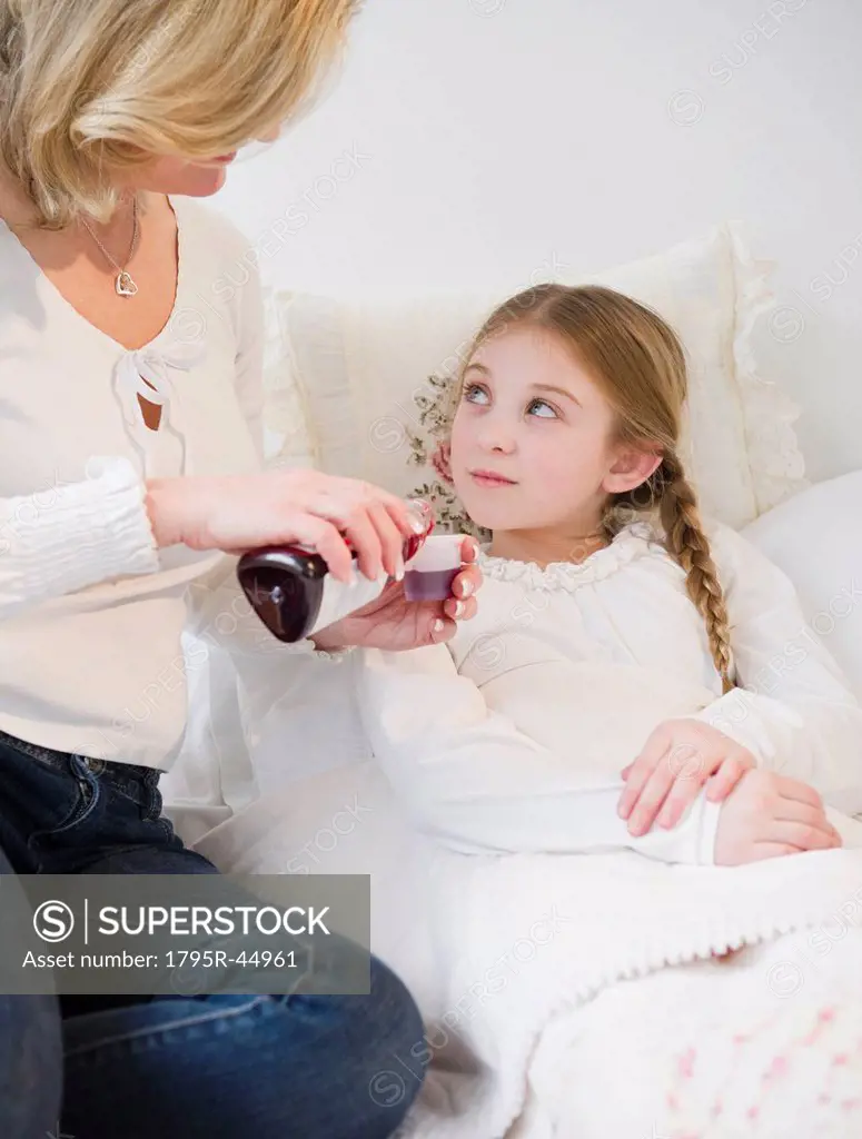 USA, Jersey City, New Jersey, mother giving medication to daughter 10_11 in bed