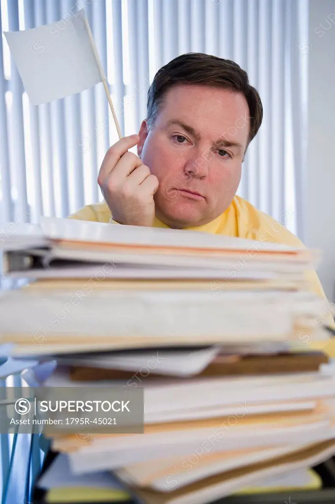 USA, Jersey City, New Jersey, businessman holding white flag over stack of paperwork