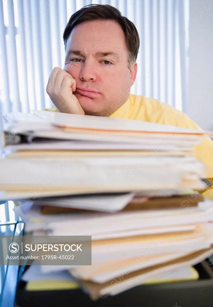 USA, Jersey City, New Jersey, businessman behind stack of paperwork