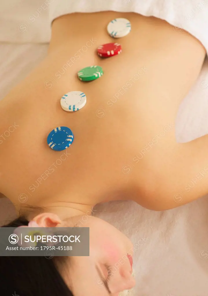 USA, Jersey City, New Jersey, woman on massage table with poker chips on back