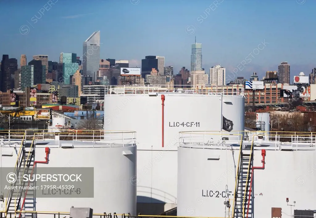 USA, New York City, Oil storage tanks in refinery with Manhattan skyline in background