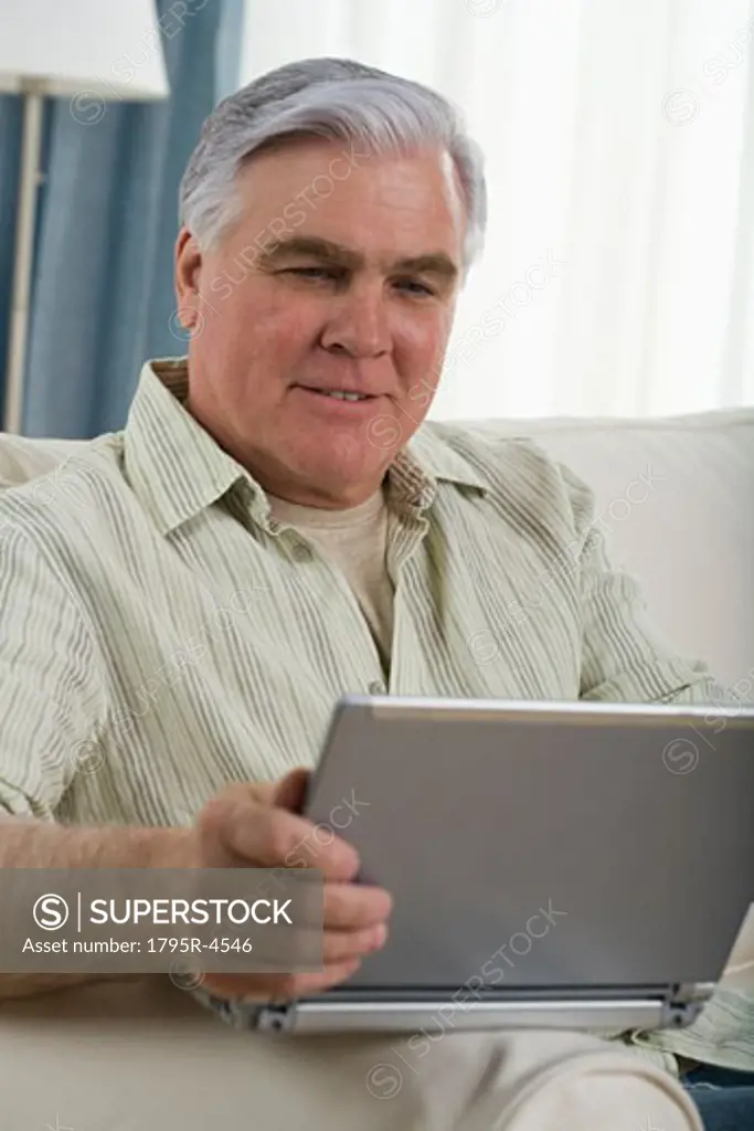 Senior man using laptop on sofa