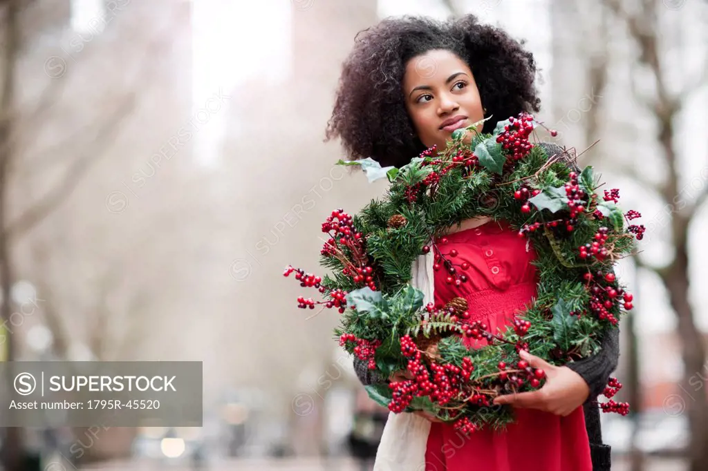USA, Washington State, Seattle, Young woman holding christmas wreath