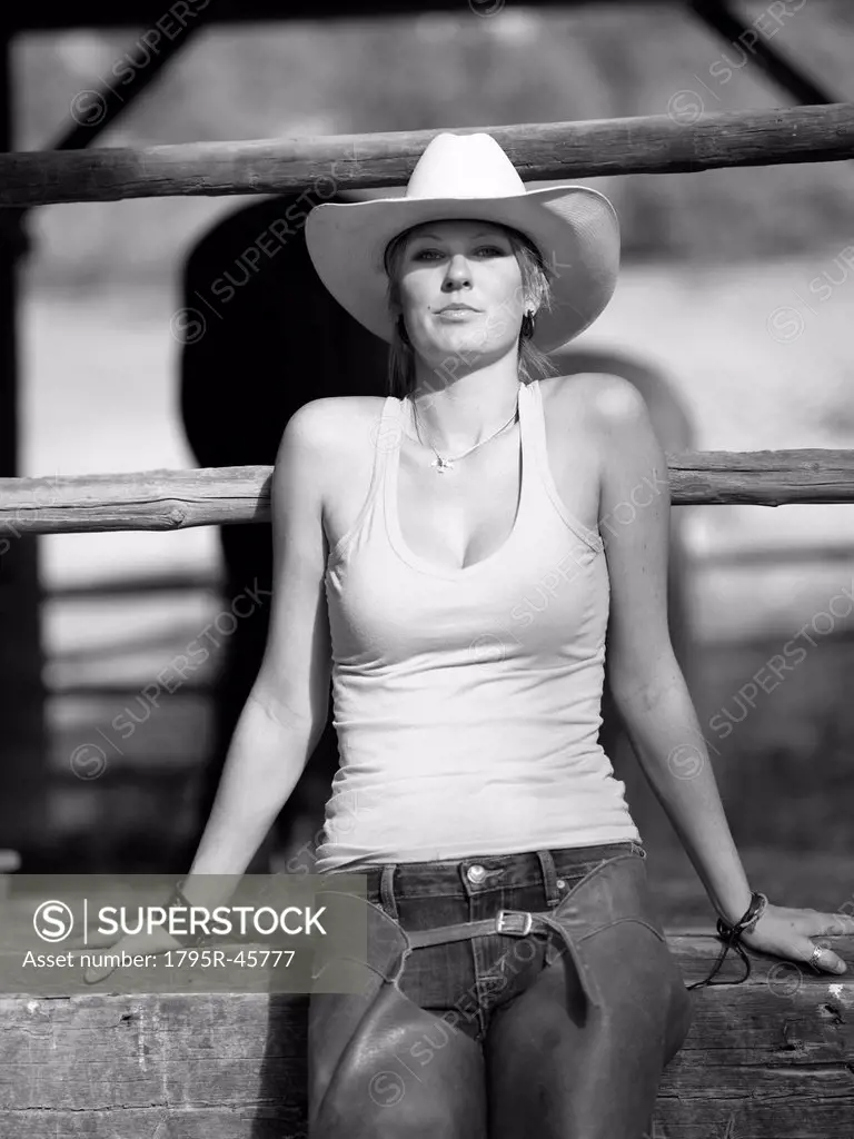 USA, Colorado, Portrait of cowgirl sitting by fence