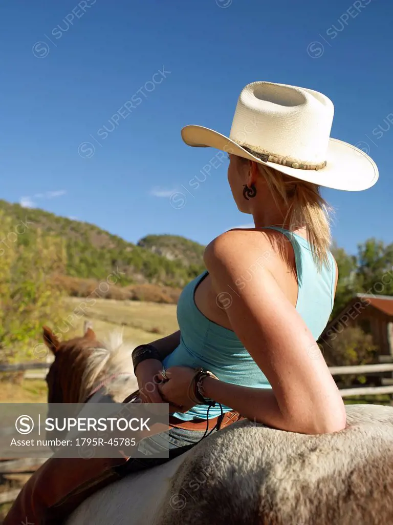 USA, Colorado, Cowgirl relaxing with horse on ranch
