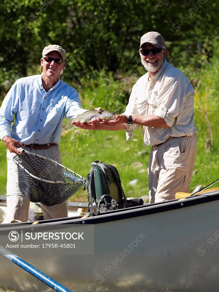 USA, Colorado, Man showing trout while standing in fishing boat