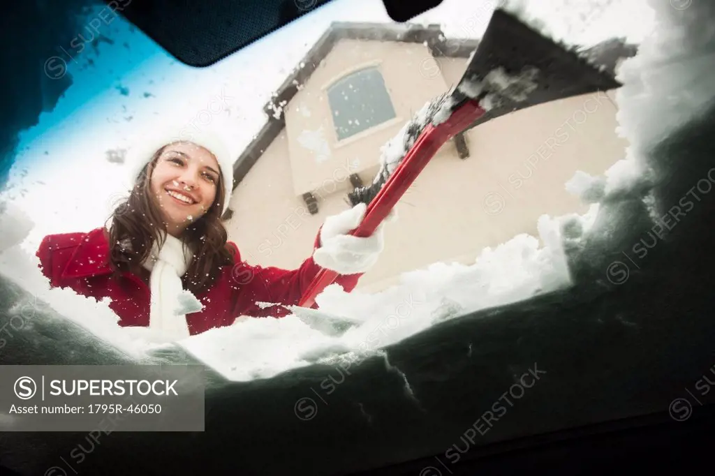 USA, Utah, Lehi, Young woman scraping snow from car windscreen