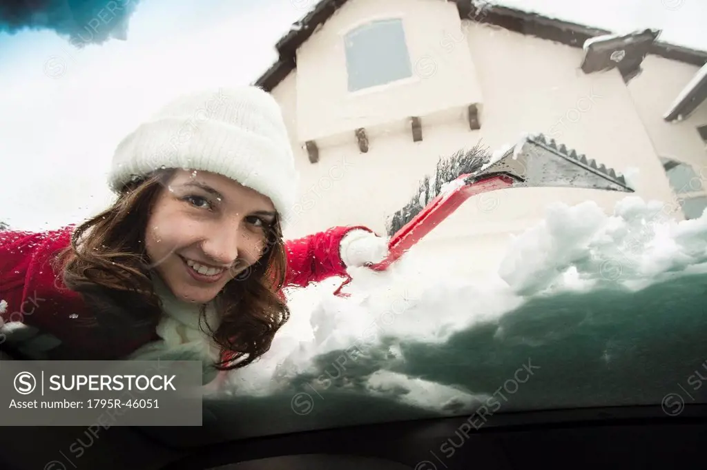 USA, Utah, Lehi, Portrait of young woman scraping snow from car windscreen