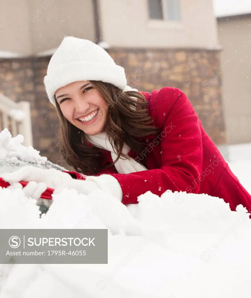 USA, Utah, Lehi, Portrait of young woman scraping snow from car