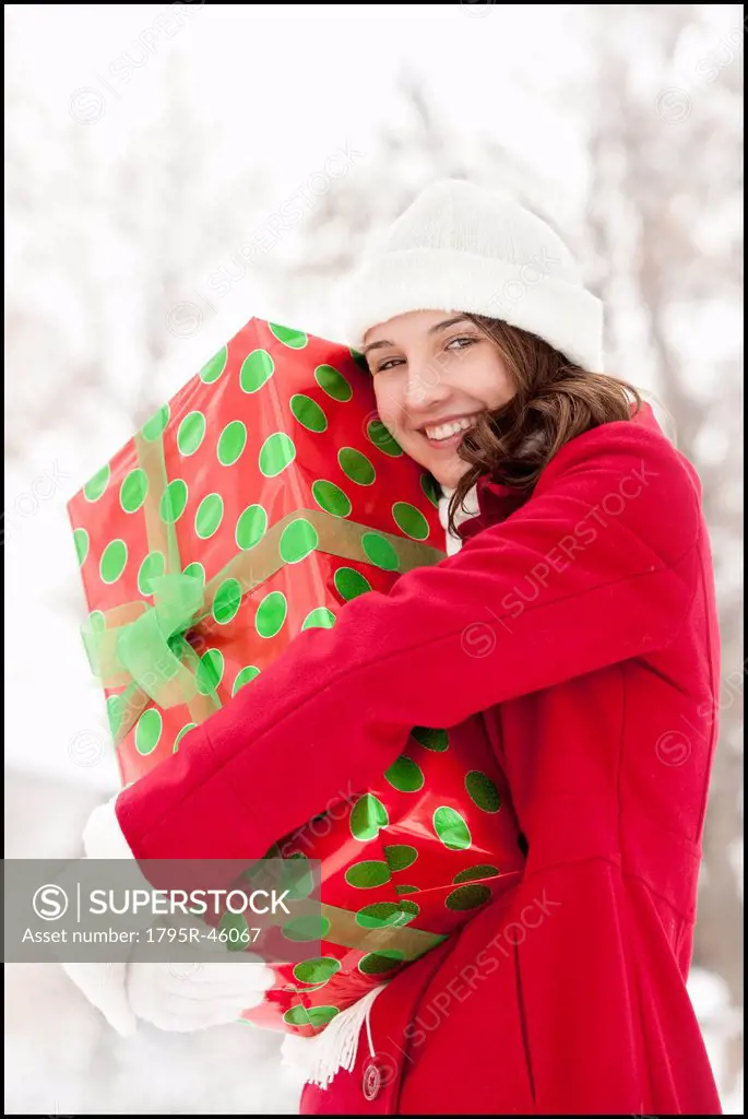 USA, Utah, Lehi, Portrait of young woman hugging Christmas gift outdoors