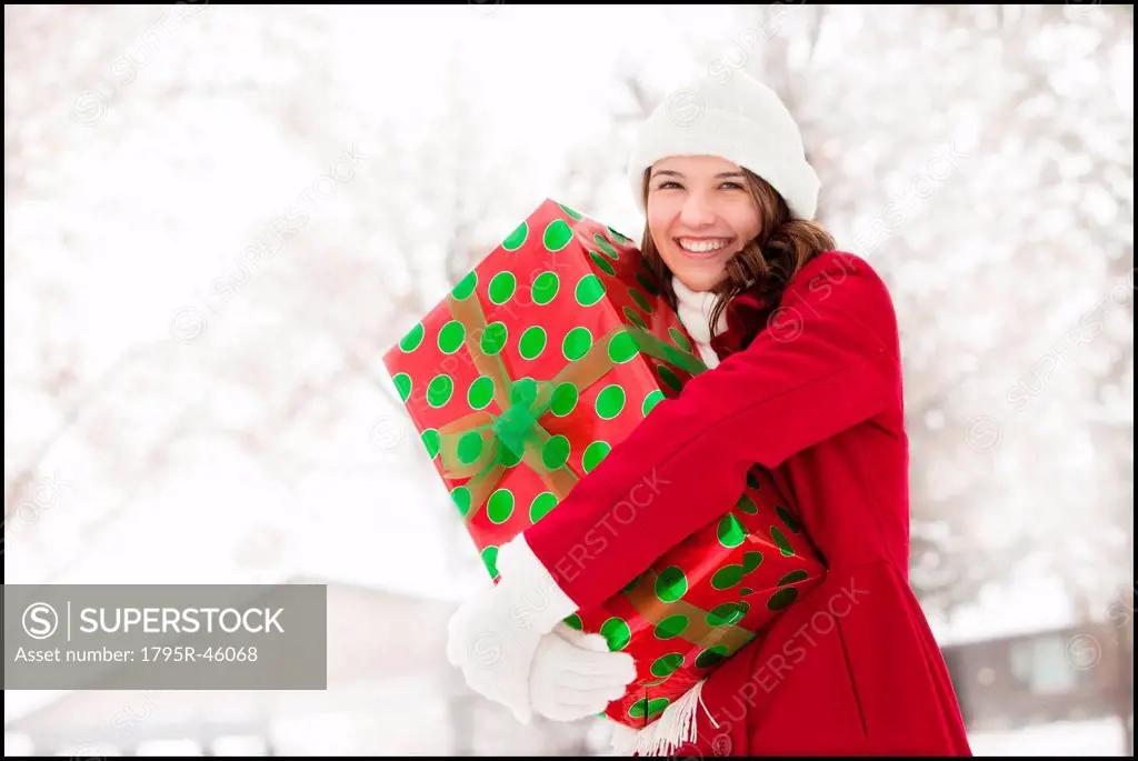 USA, Utah, Lehi, Portrait of young woman hugging Christmas gift outdoors