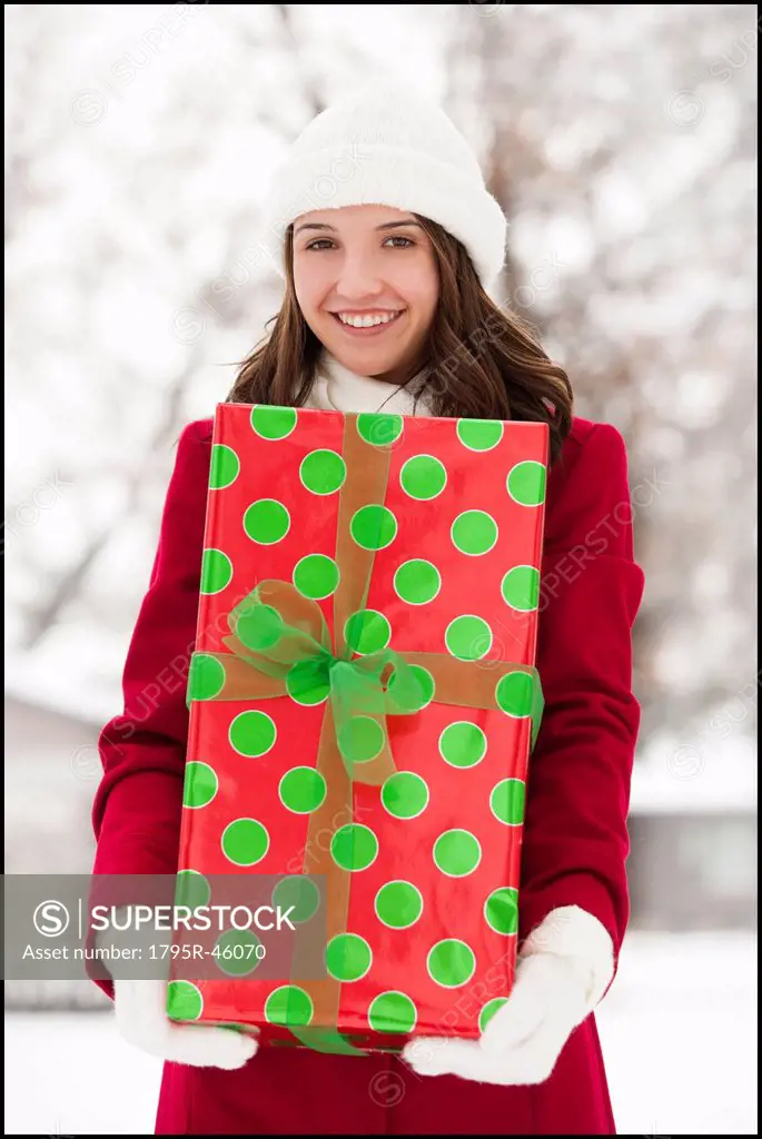 USA, Utah, Lehi, Portrait of young woman holding Christmas gift outdoors