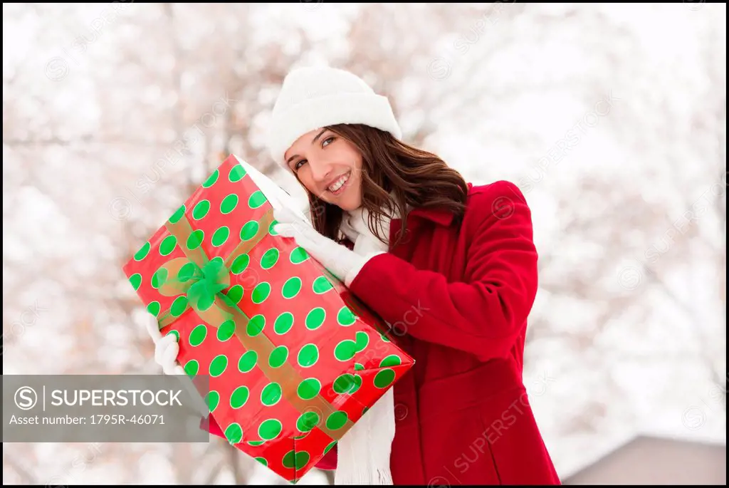 USA, Utah, Lehi, Portrait of young woman holding Christmas gift outdoors