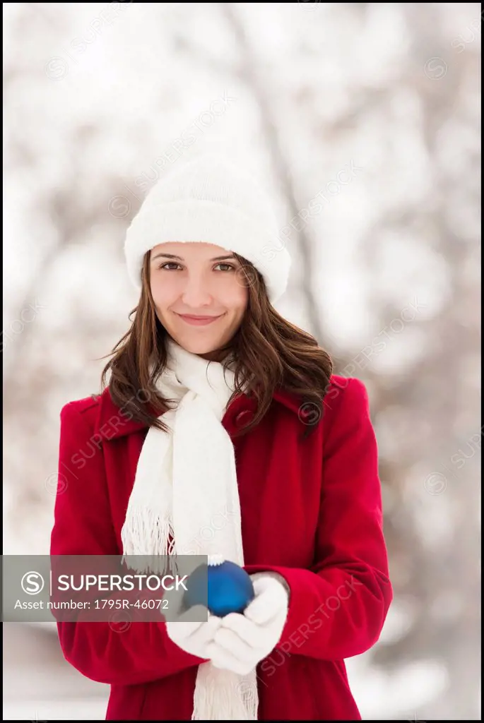 USA, Utah, Lehi, Portrait of young woman holding Christmas bauble outdoors