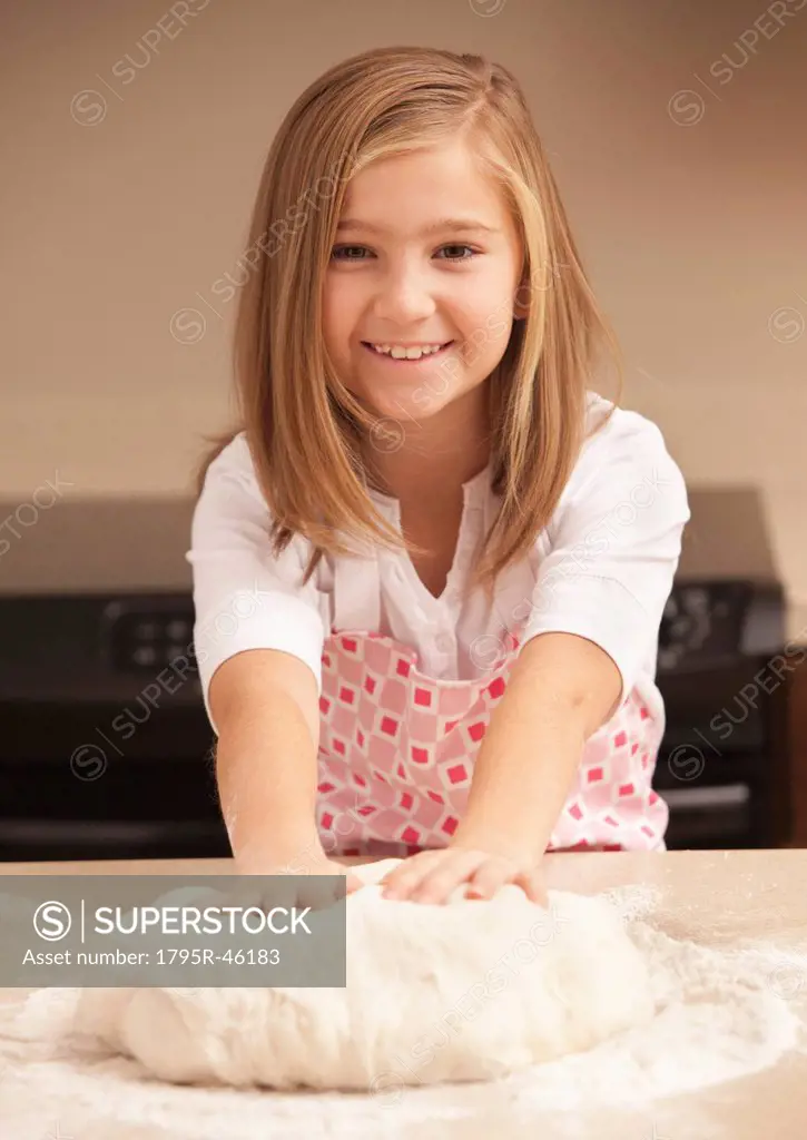 Portrait of girl 10_11 kneading dough in kitchen