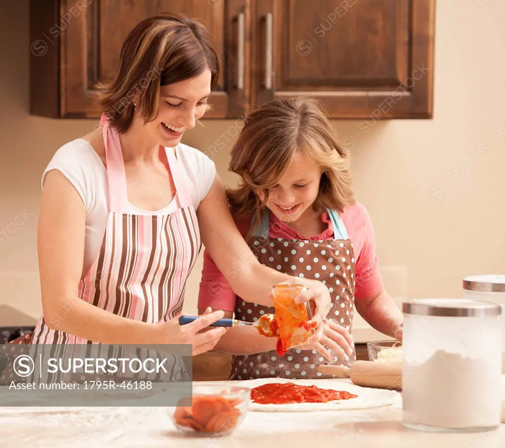 Mother and daughter 10_11 preparing pizza in kitchen