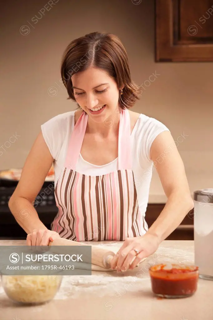 Woman preparing pizza dough in kitchen