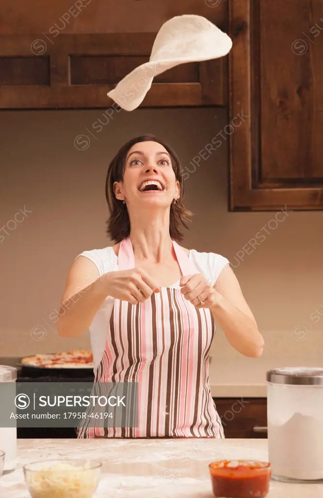 Woman tossing dough in kitchen