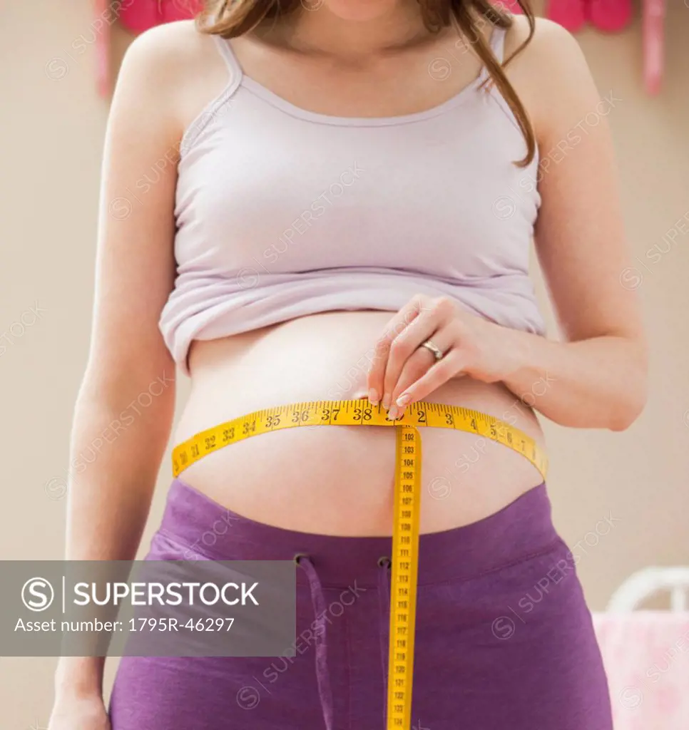 USA, Utah, Lehi, Young pregnant woman measuring belly