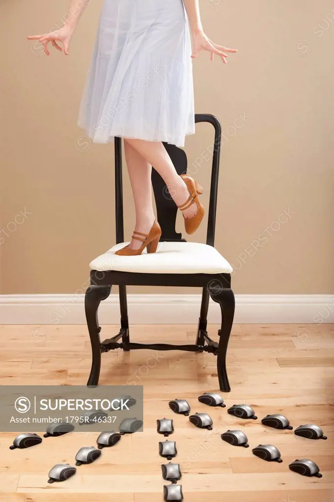 USA, Utah, Lehi, Young woman standing on chair, evading computer mice