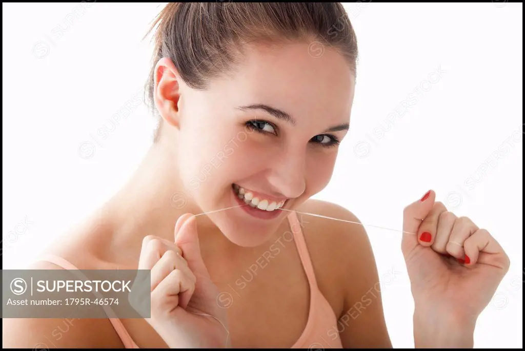 Studio portrait of young woman flossing teeth